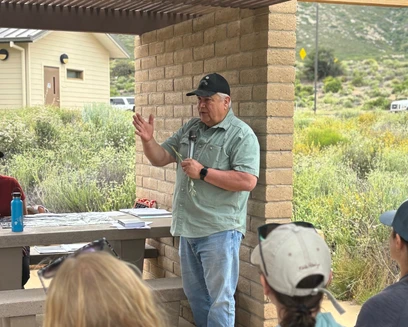 A person speaks into a microphone in front of a room of participants