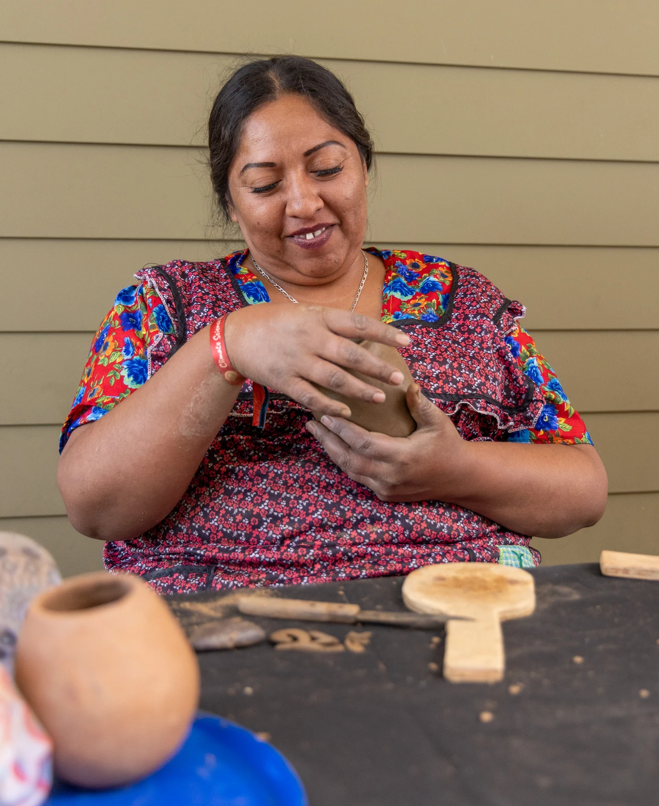A person uses their hands to form a clay pot