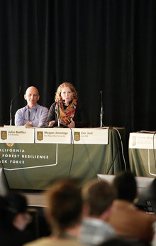 Dr. Megan Jennings speaks into a microphone at a table with fellow panelists.