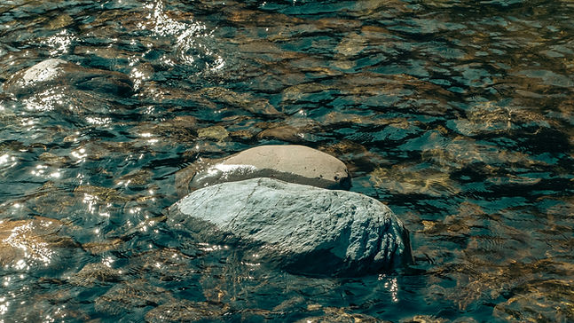 Rocas en un lago poco profundo brillando bajo el sol.