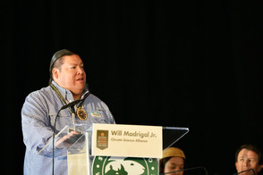 Will Madrigal, Jr. speaks at a podium as the panel discussion moderator.