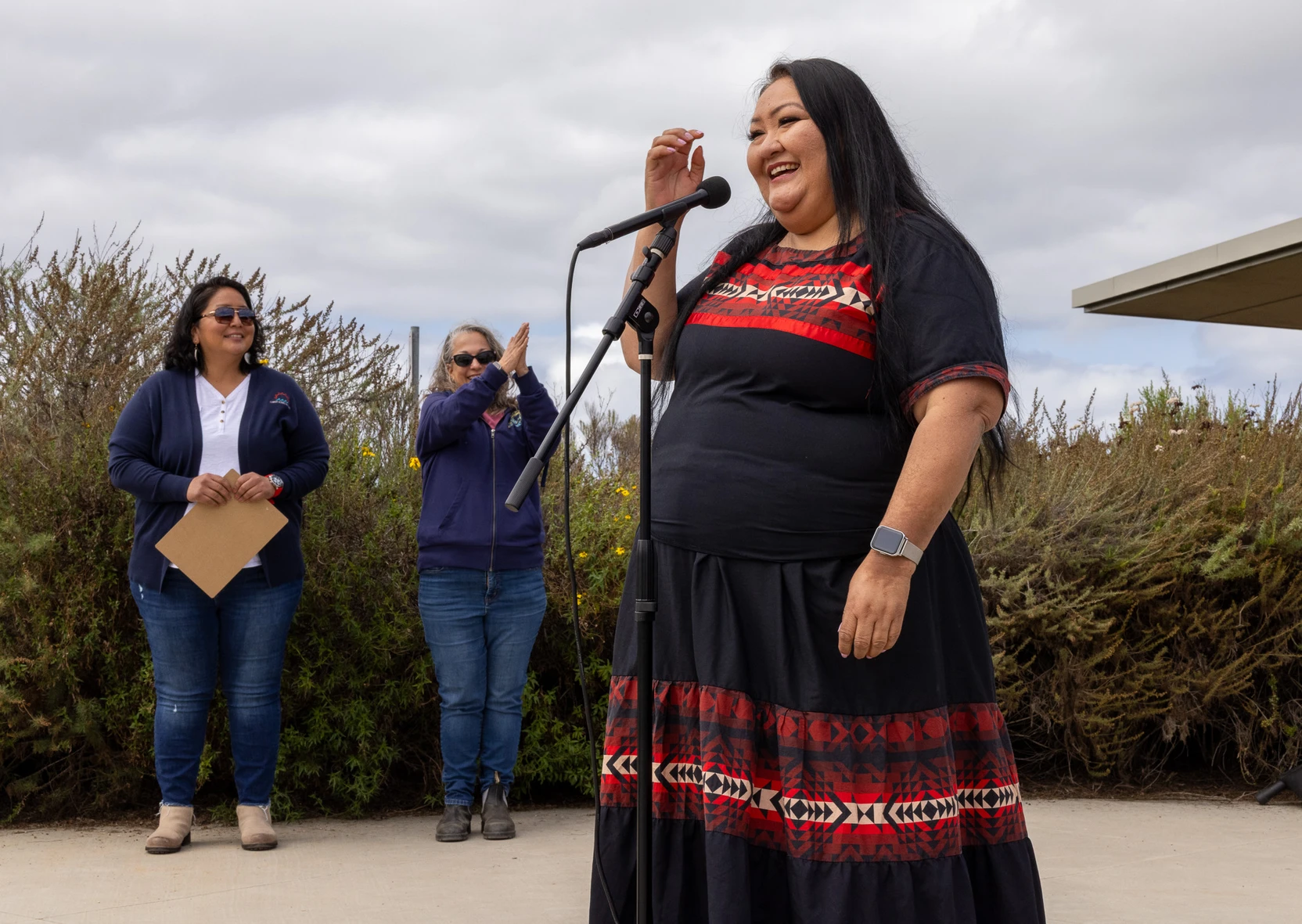 A person stands speaking into a microphone