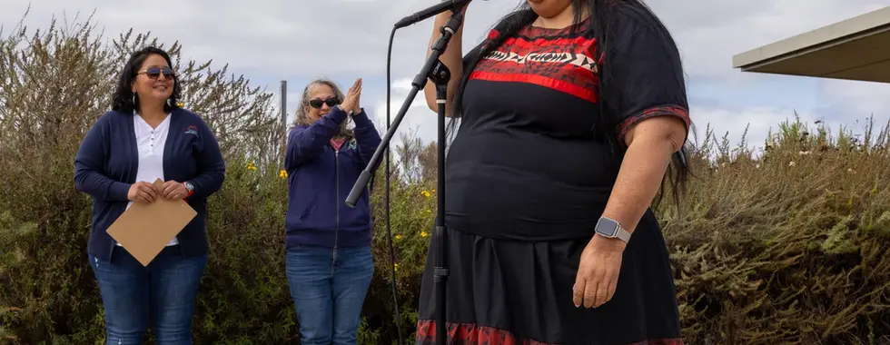 A person stands speaking into a microphone