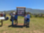 Cuatro personas con el nuevo señalamiento del sendero turtístico Mat Kiñush Tierra Bonita en un día soleado