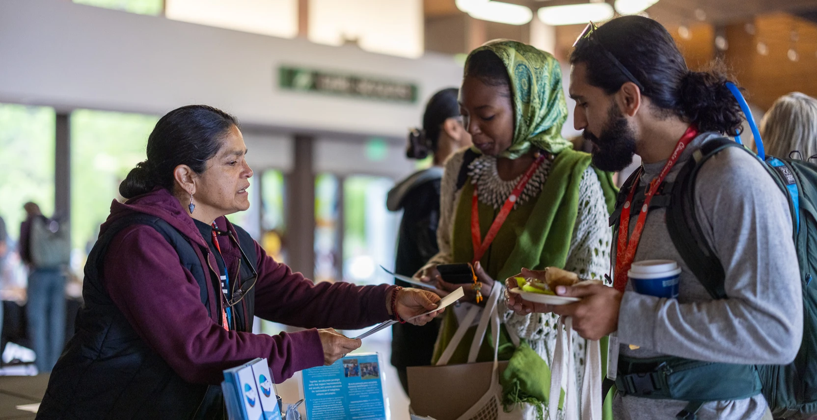 A person stands at a booth discussing their work with event attendees
