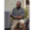 Sharpe Services AC Tech working on an outdoor condensing unit, smiling.
