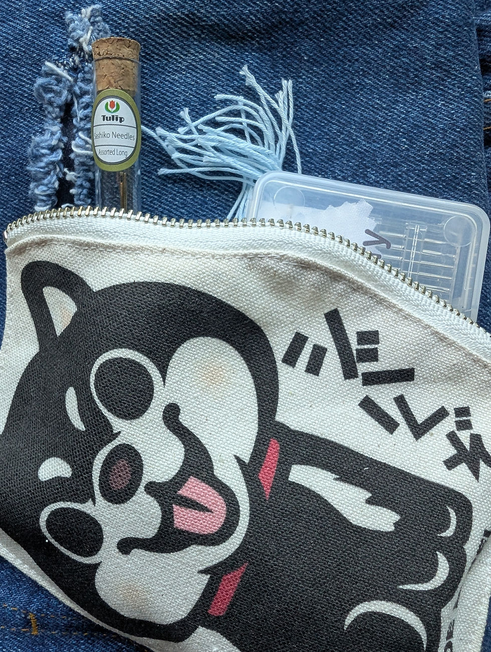 Japanese cloth zippered bag with dog design, containing sashiko mending supplies
