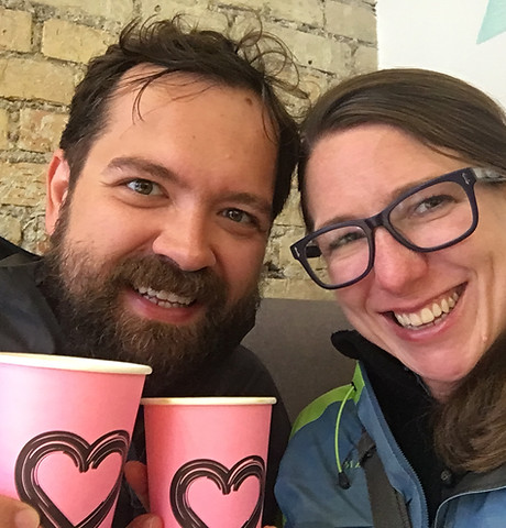 Picture of Carolyn and Marek, both smiling, holding pink disposable coffee mugs with hearts on them.
