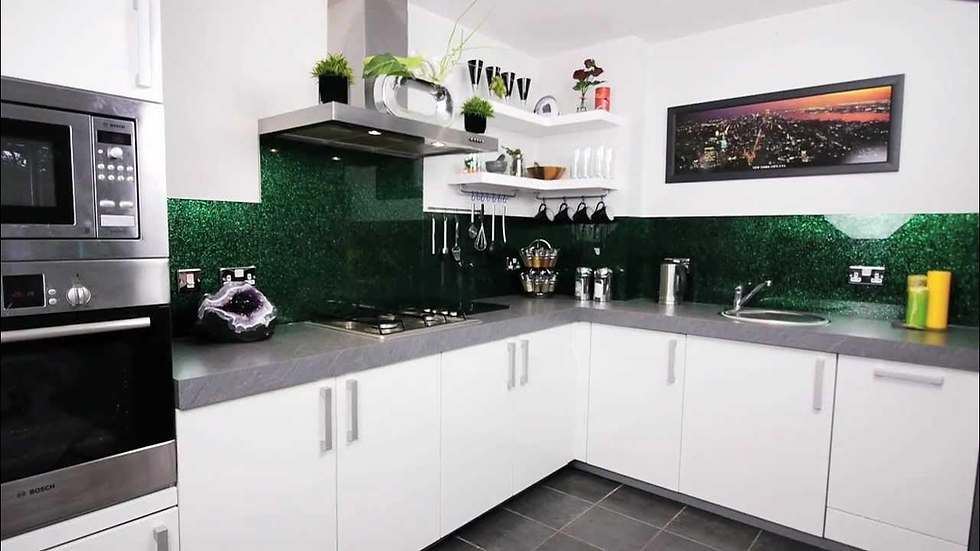 a white kitchen with a dark green glass splashback with a speckled effect