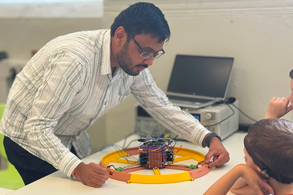 Milaan Patel demonstrating how scientists accelerate particles with the ‘Tabletop Ball Bearing Accelerator’.