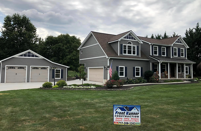 FrontRunner Construction crew installing new grey vinyl siding and a matching asphalt roof on a house and shed in Adams County, Pennsylvania.
