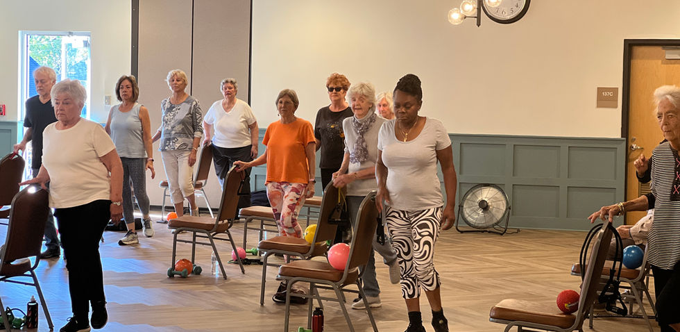 Seniors participating in a group exercise class with chairs.