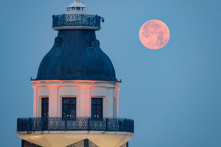 a full moon rises over a building with a balcony