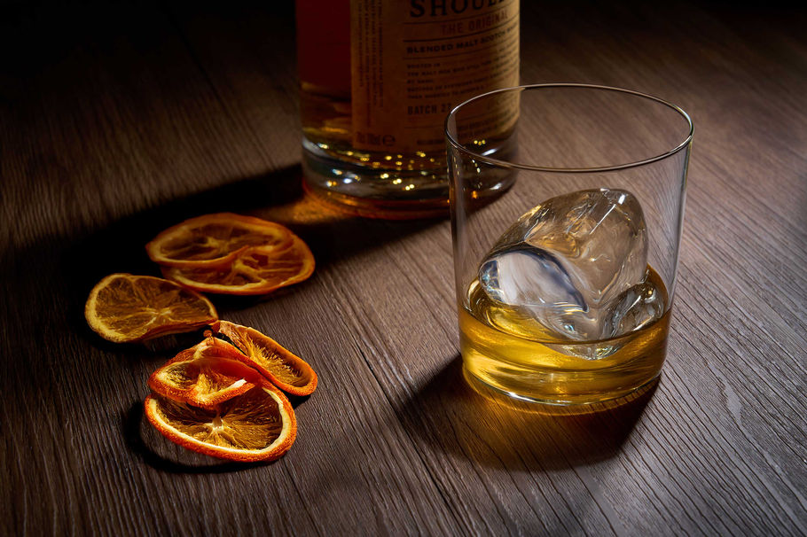 Stunning shot of a golden whiskey on ice with dried orange slices, perfect for an evening unwind. Captured by an expert drinks photographer in Brighton, serving Sussex and beyond.