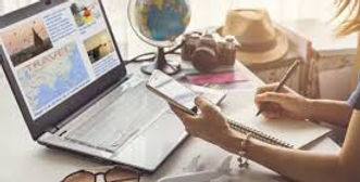 Traveler planning a vacation with a laptop, map, camera, and travel essentials