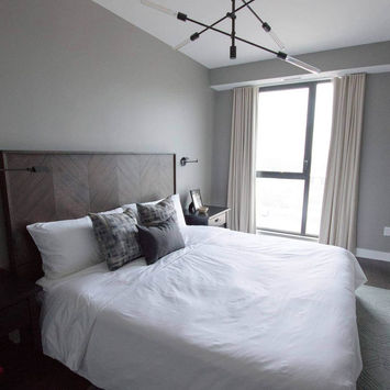 Modern grey bedroom in Griffintown Montreal with freshly painted walls, white bedding, and natural light – interior painting by Maple Wood Painting.
