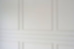 Close-up view of an elegant white wall with decorative rectangular wainscoting panels and molding detail in a home interior in Griffintown, Montreal.