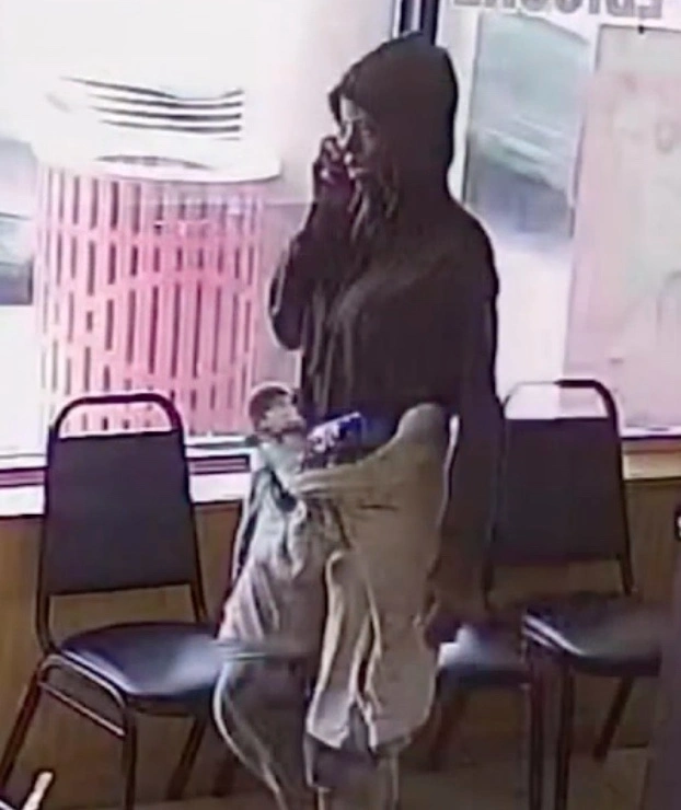 Security camera footage screenshot of TiJae in grey sweatpants and a black sweatshirt making a phone call