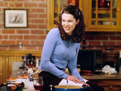 Lorelai Gilmore in Gilmore Girls sitting on a counter in Max Medina's apartment wearing a blue long sleeve shirt