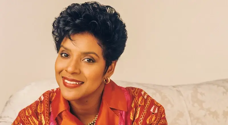 headshot of Claire Huxtable from the Cosby Show in an orange collared shirt