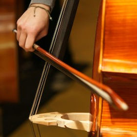 A man bowing the strings of a double bass.