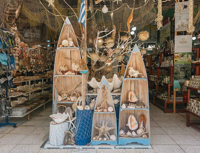 "Front display of Machos Tourist Shop in Corfu, showcasing sea-themed souvenirs like shells, starfish, and coral on boat-shap