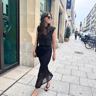 Klare Linie, dunkle Farbe, verspielte Details. Das Outfit wirkt ruhig, aber interessant.