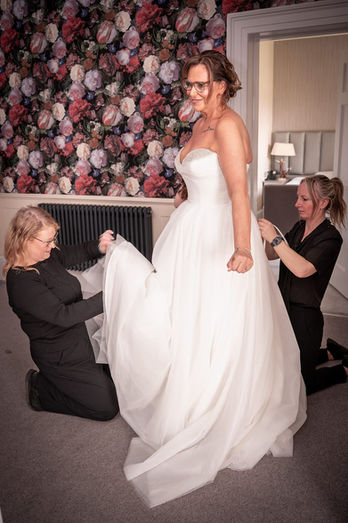 Lisa being helped into her wedding dress by friends in the bridal suite at Bartle Hall, Preston