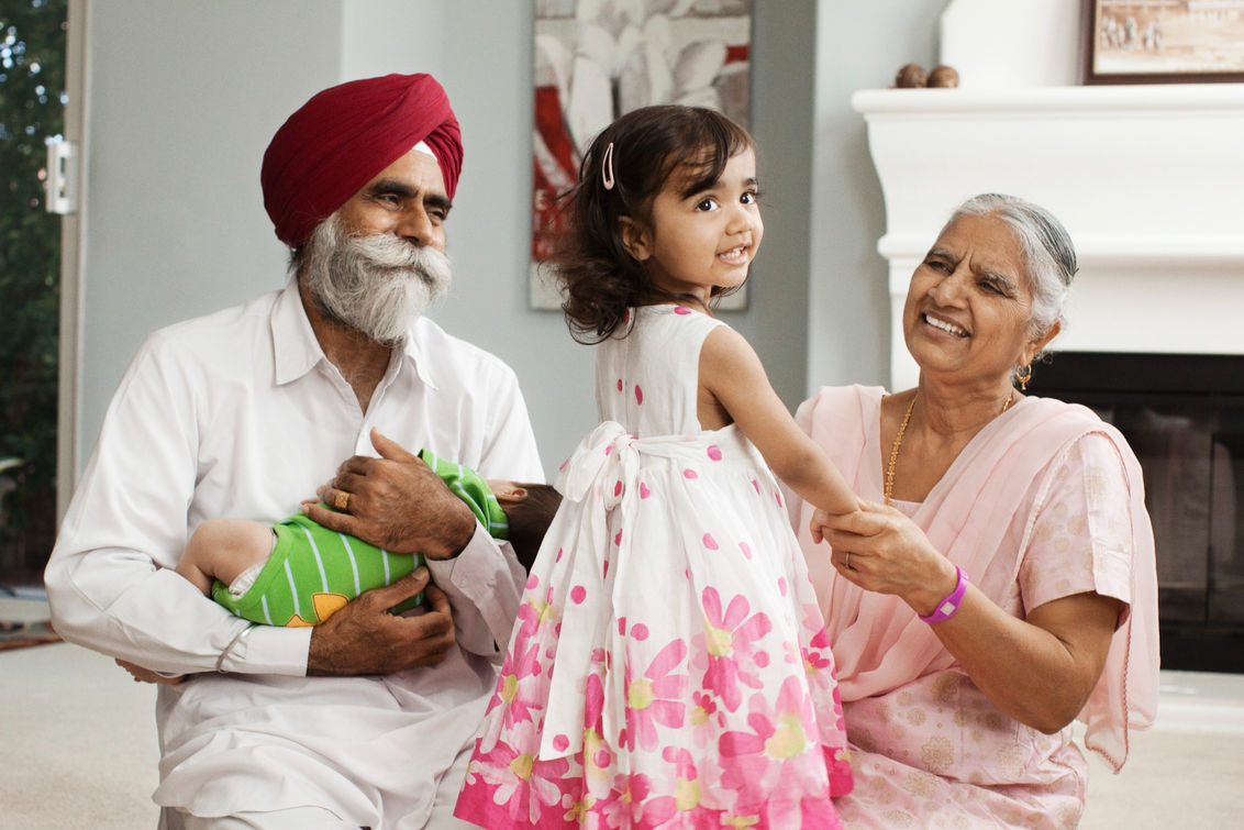 Grandparents laughing and holding their 2 grandchildren