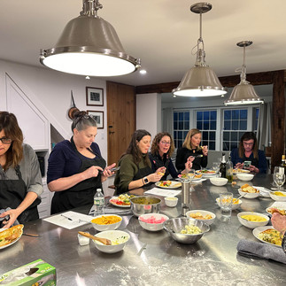 people cooking around an island at a cooking workshop
