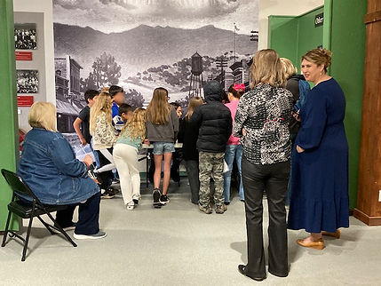 Teachers and students stand around a table while being taught about Native American culture.