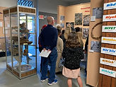 A male teacher and students are standing in the Yokuts exhibit.