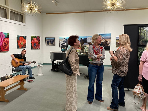 Joy of Life artist reception with Melinda Scott, attendees, and guitar player.