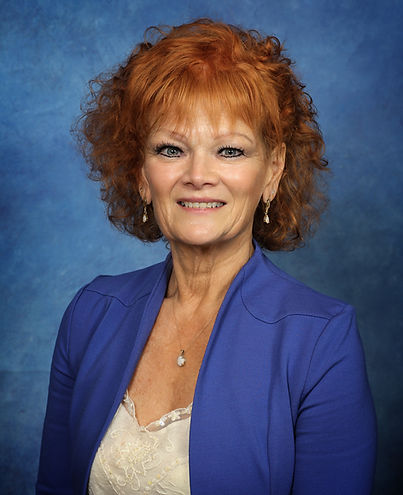 Patty Spott wears a blue blazer with a blue textured backdrop.