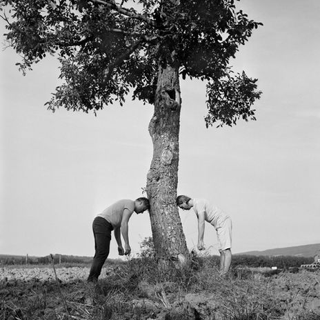 Black and white photograph of two people leaning on a tree by artist Roman Franc. 