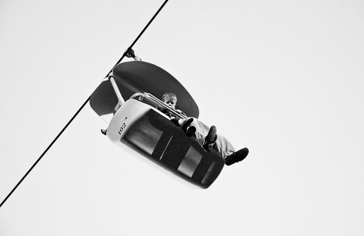 Black and white photography of a curious boy looking down from a bucket ride by Little Rock artist Katie Adkins. 