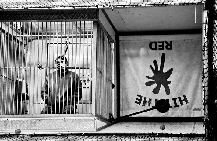 Black and white photograph of a carnival worker behind bars by Little Rock artist Katie Adkins. 