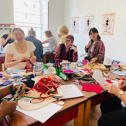 A group of workshop people laughing and chatting as they take part in a textiles workshop in Bath