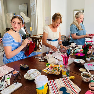A group of people in Regency costume hand sewing as part of a Jane Austen creative workshop in Bath