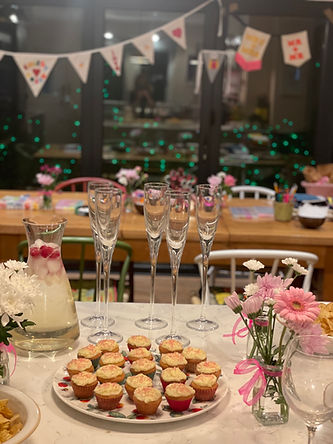 A room decorated with table set for a hen party with glasses and cupcakes