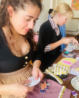A young woman in Regency costume hand sews a reticule during a creative workshop by Make Creative Studio in Bath