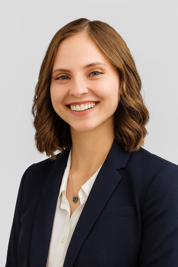 Portrait profile photo of a smiling woman in a navy blazer on a light background
