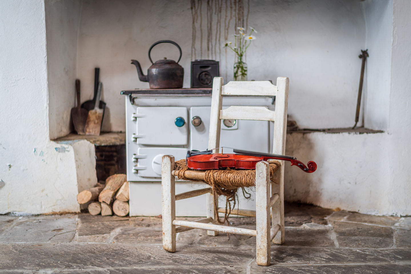 a violin sits on a chair in front of a white stove