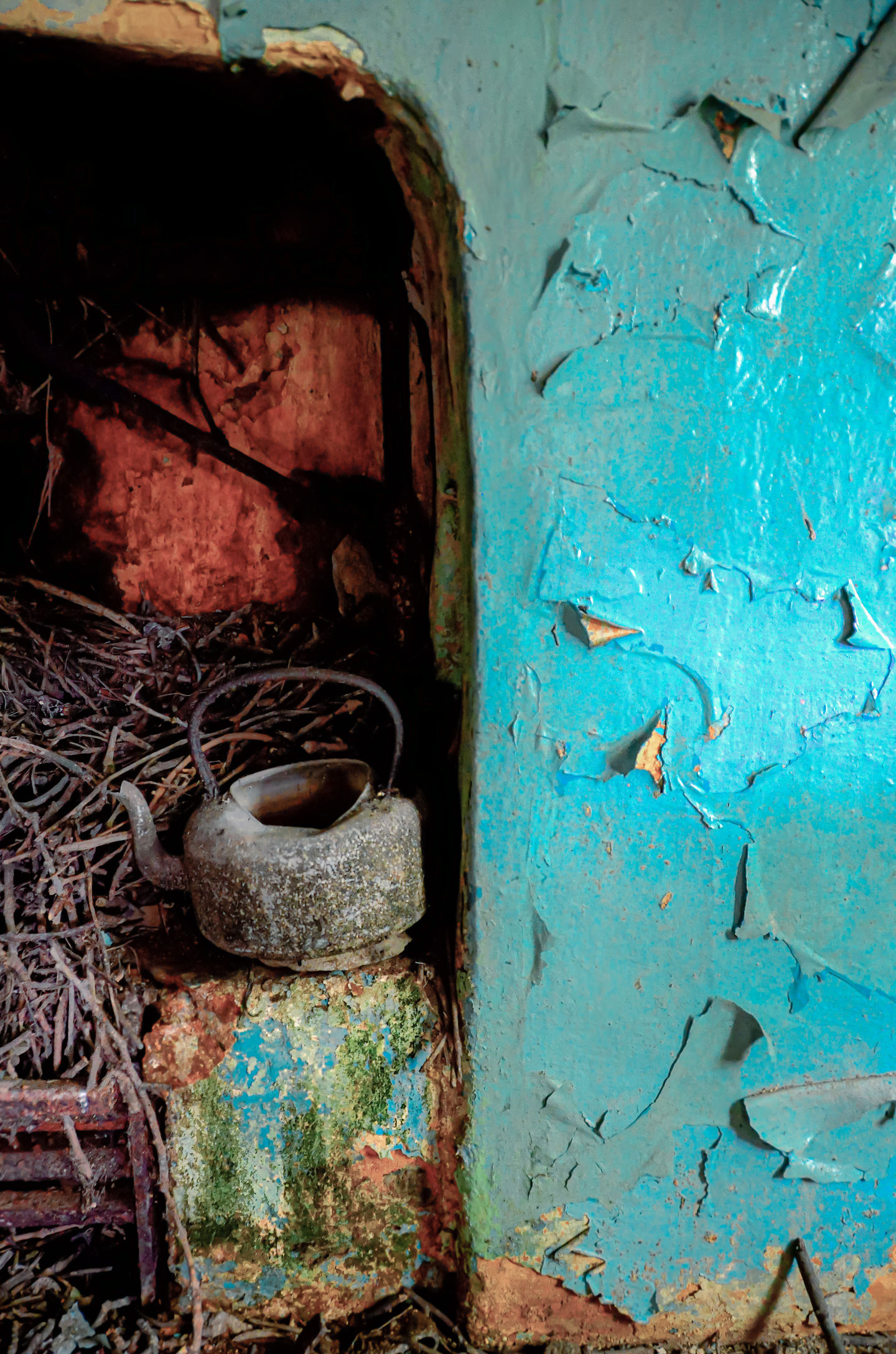 a rusty tea kettle sits next to a blue wall
