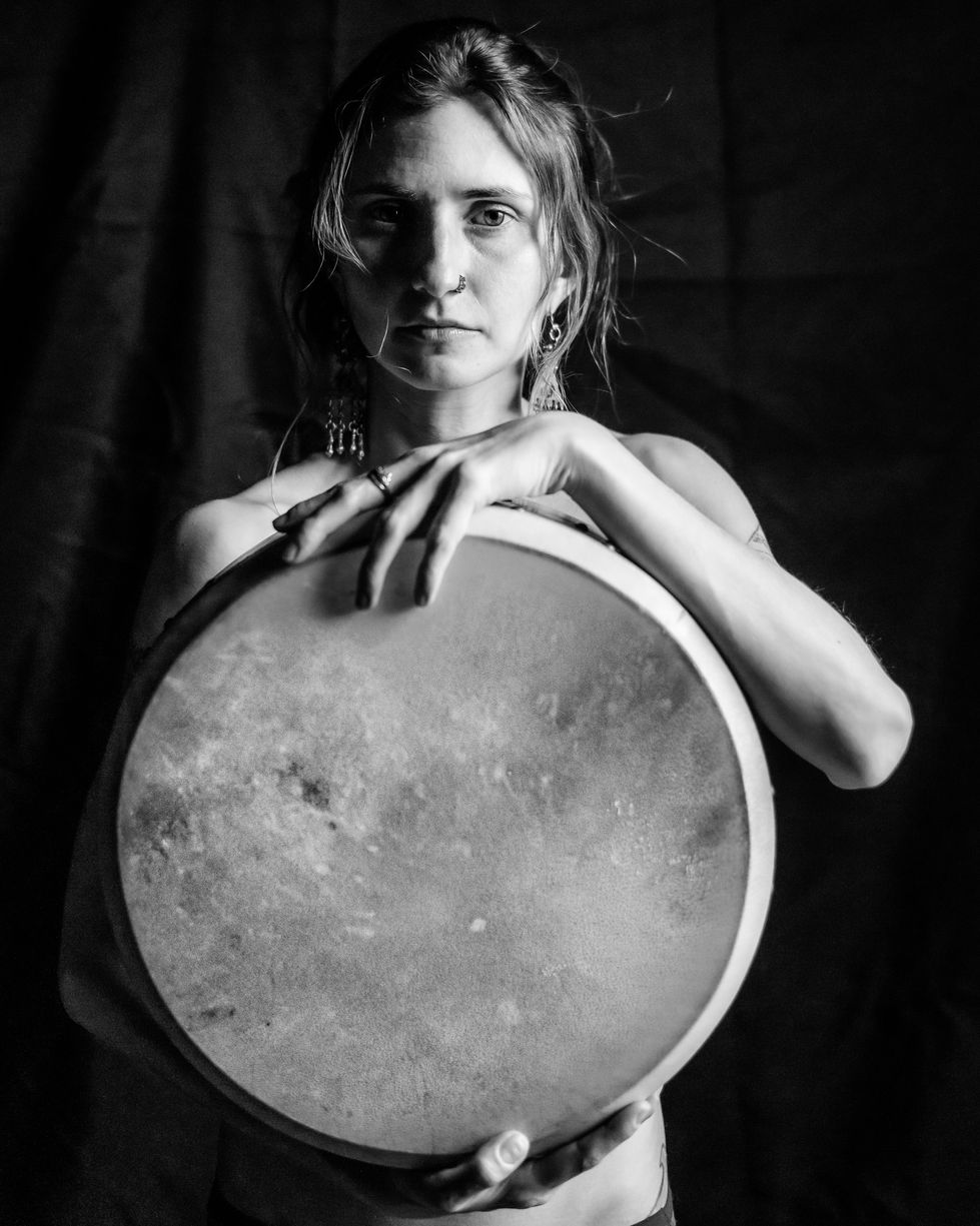 a black and white photo of a woman holding a drum