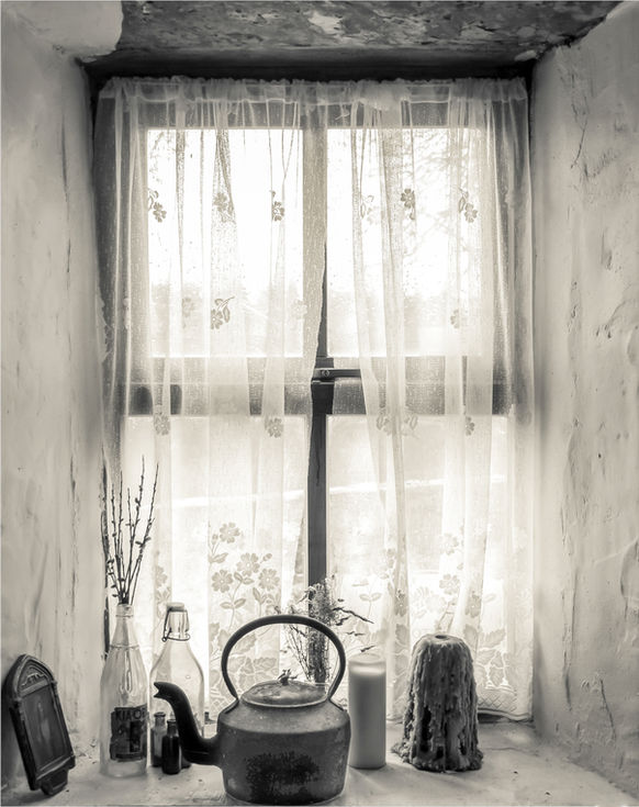 a black and white photo of a window with a lace curtain