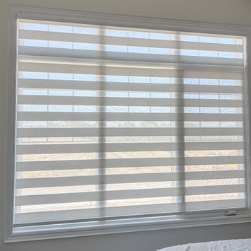 Zebra blinds installed on a wide window with layered fabric design