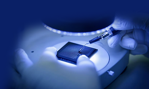 Gloved hands testing a microchip under a microscope with a precision probe