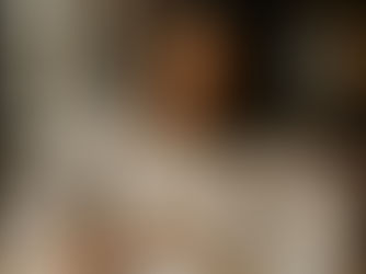 A woman writing in a notebook at a cozy café table with a cup of coffee, reflecting quietly in a warm, peaceful setting.