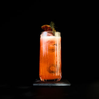 Cocktail signature à la vodka avec prémix maison fraise et combava décoré de pomelo séché sur fond noir